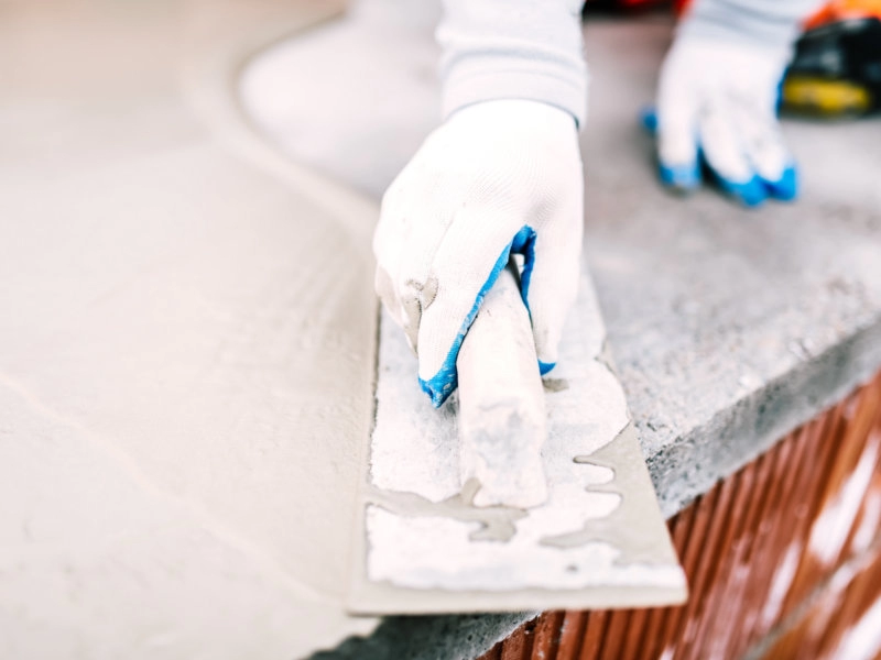 Detailaufnahme einer Glättkelle, mit der frischer Putz auf eine Wand aufgetragen und geglättet wird – typische Arbeit bei Putz- und Fassadenarbeiten.